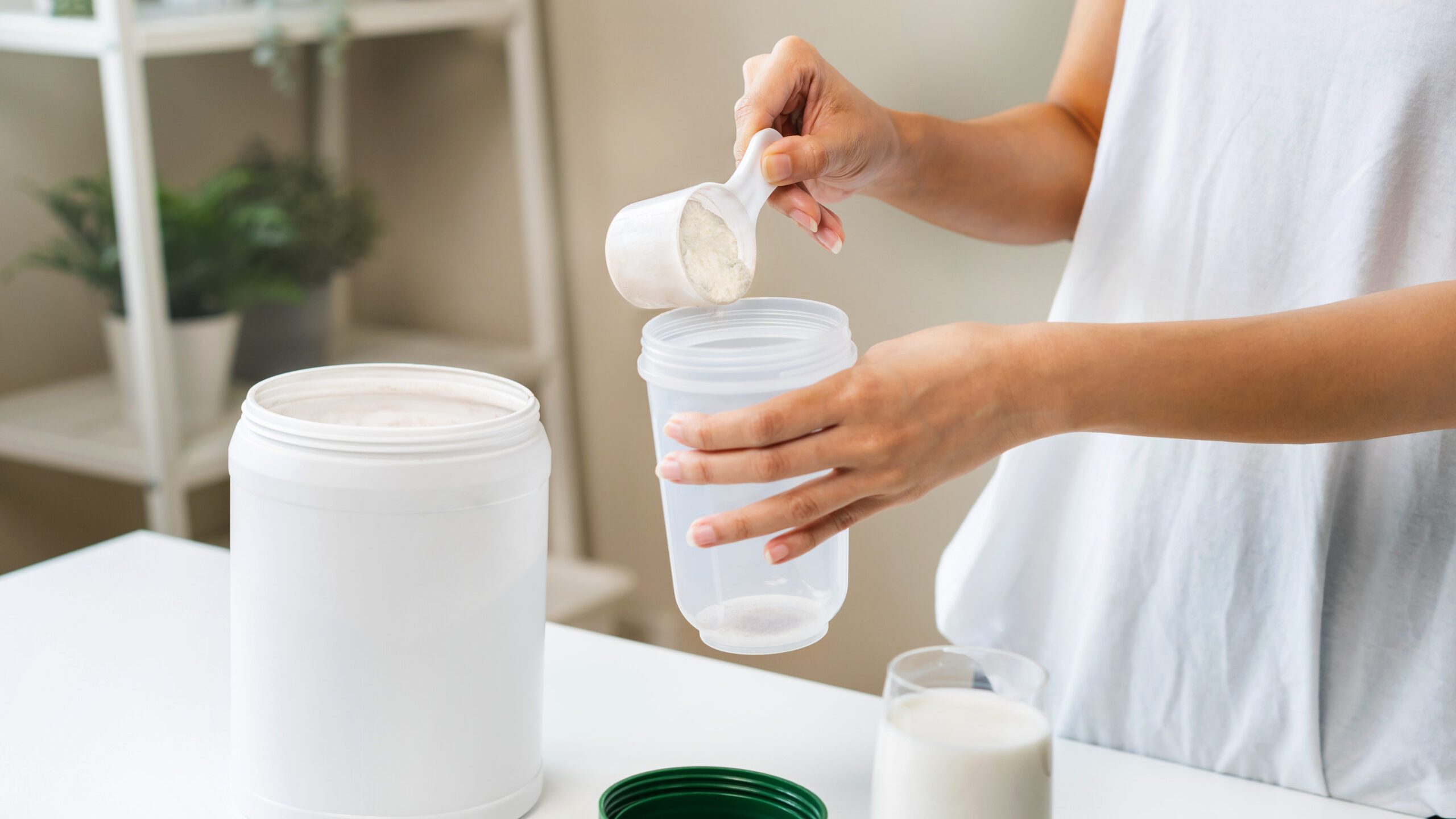 Diet meal replacement for weight loss, smile asian young woman, girl in sportswear, hand in holding scoop making protein shake, drink supplement for muscle after workout at home. Healthy body care.